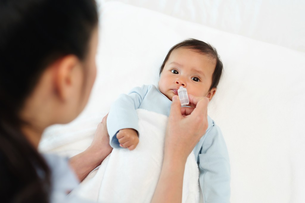 The newborn child receives nasal drops from the mother in bed